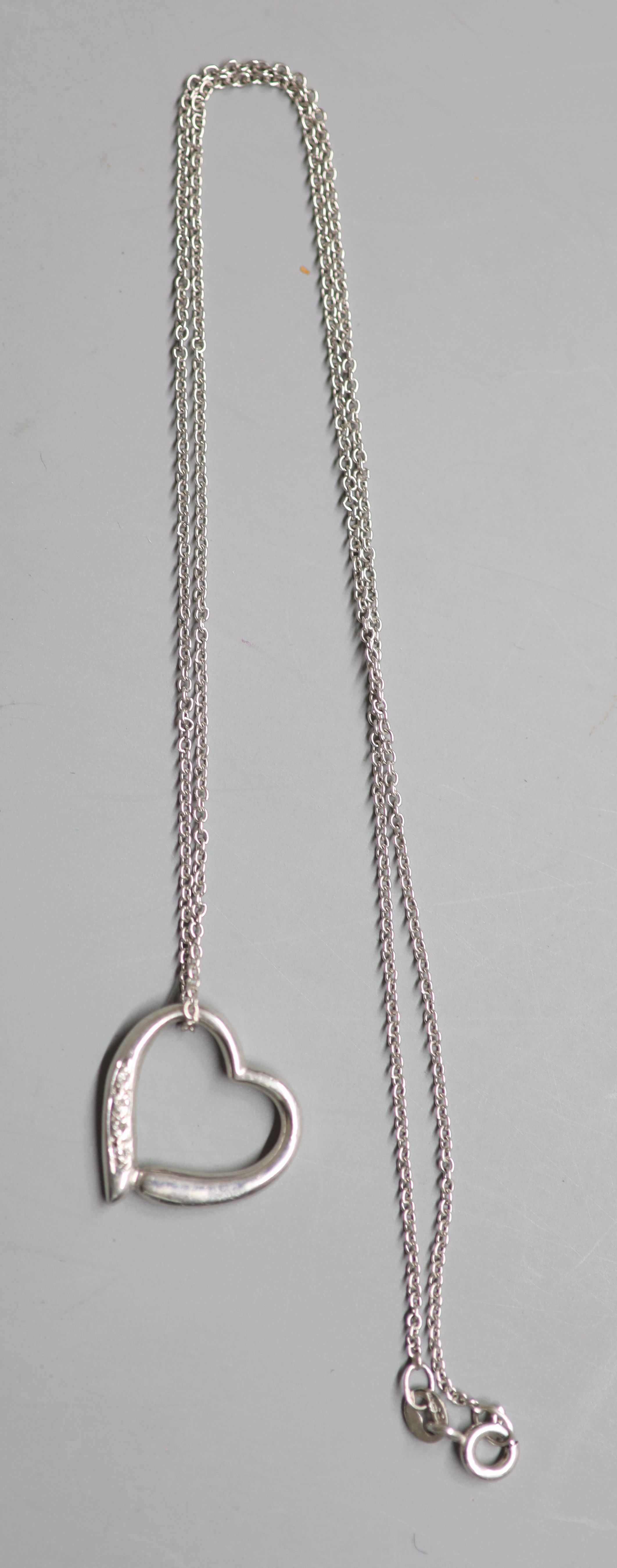 A modern 9ct white gold and diamond chip set openwork heart pendant, 18mm, on a 9ct white gold chain, 39cm, gross 3.8 grams.